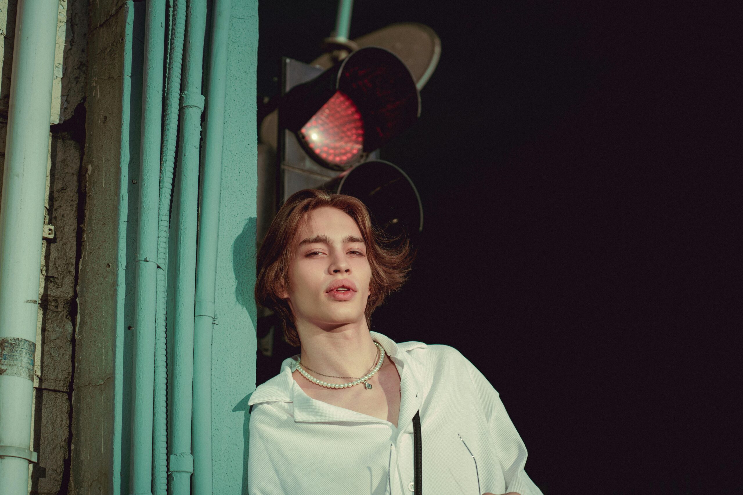 Stylish young adult posing confidently by a traffic light in Istanbul, showing modern fashion sense.